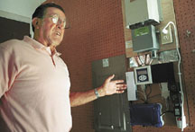 Caruso points to the control panel for his solar system, where its DC electricity is converted to AC for his home's electrical needs. A computer readout on the panel allows him to monitor energy output and consumption. (Erik Petersen photo)