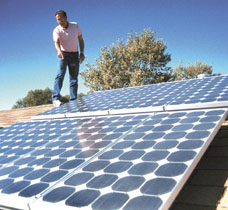 Standing on the roof of his Green Acres home recently, Dick Caruso explains how the solar panels for his solar energy system work. (Erik Petersen photo)